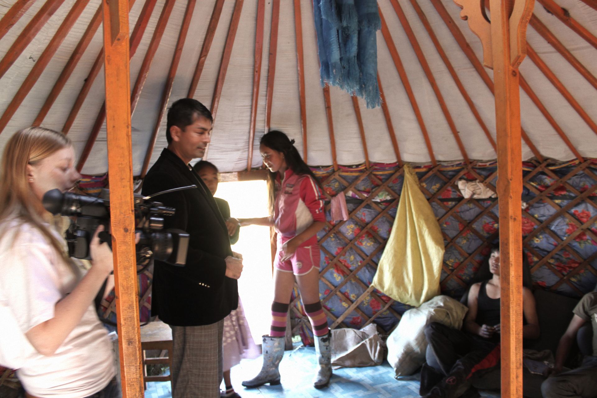 Field research inside a traditional Mongolian ger, with a camera operator filming a conversation